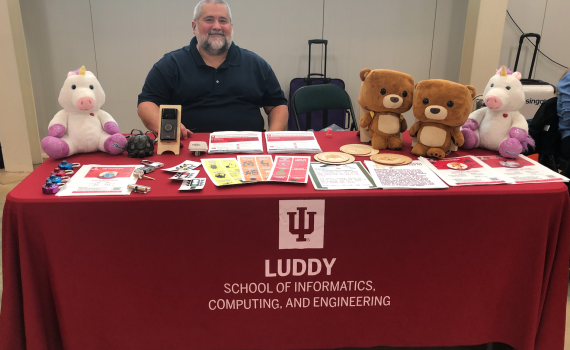 Joshua Streiff Sitting at Table with Research Toys and Games Promoting the Luddy School of Informatics, Computing & Engineering